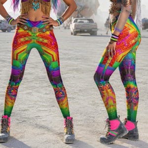 May include: Three models wearing colorful leggings and tops with the "7BYTE CLOTHING" logo. The leggings feature a vibrant geometric design in rainbow colors. The models are in a desert setting, with cars and structures in the background.