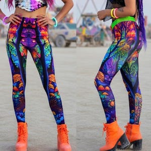 May include: Three women wearing matching leggings with a colorful, psychedelic mushroom design. They are also wearing sequined tops, neon accessories, and orange platform boots. The leggings have a dark blue background with vibrant orange, green, and purple details.
