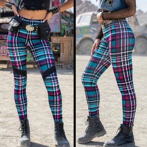 May include: Three women modeling colorful plaid leggings with black accents. The leggings feature a pattern of teal, pink, and white lines. Each model wears a different top, including a black mesh top, a studded crop top, and a denim vest.