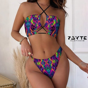 May include: A two-piece swimsuit with a colorful geometric pattern. The top has a halter style with a criss-cross design and a cutout in the front. The bottom is a high-cut style with a cheeky fit. The swimsuit is made of a stretchy, comfortable fabric. The brand name "PSYTE CLOTHING" is printed on the bottom right corner of the image.