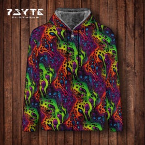 May include: A zip-up hoodie with a vibrant, psychedelic pattern in shades of green, purple, orange, and blue. The jacket has a gray, fuzzy interior lining and the brand name "7AYTE CLOTHING" is visible at the top left.