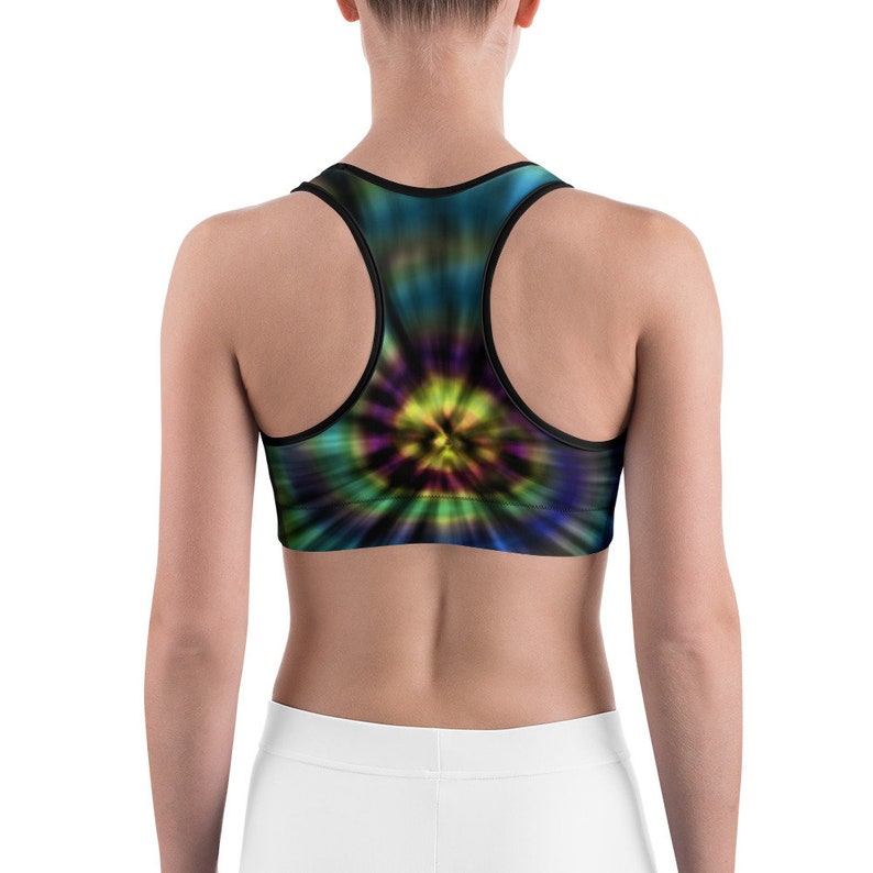 May include: A tie-dye sports bra with a vibrant, swirling pattern in shades of blue, green, yellow, and purple. The bra has a racerback design and a black trim. The back of a person is visible, wearing the bra.