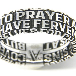 May include: A silver ring with the words "Pray and Have Fervent Prayer for God to Cover All Sins" engraved around the band.