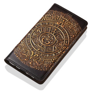 May include: A black leather wallet featuring a gold embossed design of the Aztec calendar. The design is intricate and detailed, with a central sun god figure.