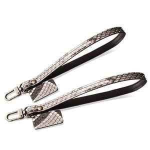 May include: Two brown leather straps with a snakeskin pattern and a metal clasp. Each strap has a small snakeskin tag attached.