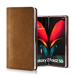May include: A brown leather phone case with a Samsung Galaxy Z Fold2 5G phone inside. The phone is open and the screen is showing a red and blue abstract design.