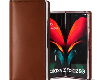 Puede incluir: Una funda de cuero marrón plegable para un Samsung Galaxy Z Fold2 5G. La funda se muestra en posición cerrada a la izquierda y abierta a la derecha, revelando la pantalla interior que muestra el texto Galaxy Z Fold2 5G y August 5.