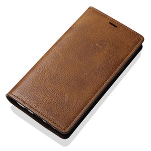 May include: A brown leather phone case with a textured surface.
