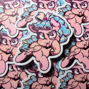 May include: A stack of pink and blue cartoon pony stickers with a tongue sticking out. The pony has a blue and yellow curly mane and tail. The stickers are printed on white paper.