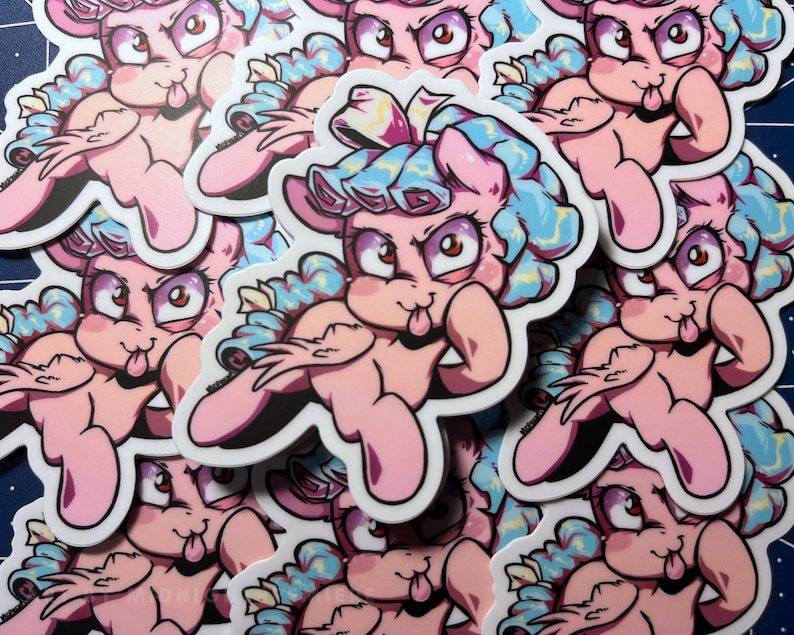 May include: A stack of pink and blue cartoon pony stickers with a tongue sticking out. The pony has a blue and yellow curly mane and tail. The stickers are printed on white paper.