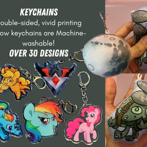 May include: A collection of colorful, double-sided, machine-washable pillow keychains. The keychains feature various designs, including a cartoon pony, a moon, a creature with wings, and a cartoon creature with a helmet. The text "KEYCHAINS" and "OVER 30 DESIGNS" is visible in the image.