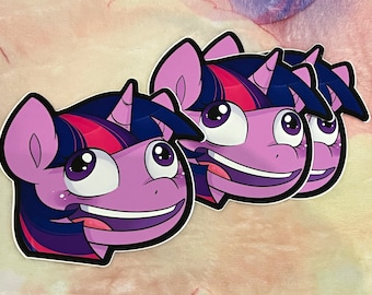 Può includere: Tre adesivi per la testa di pony di cartone animato viola e blu con occhi grandi e un grande sorriso. Il pony ha il naso rosa e una criniera rosa e blu.