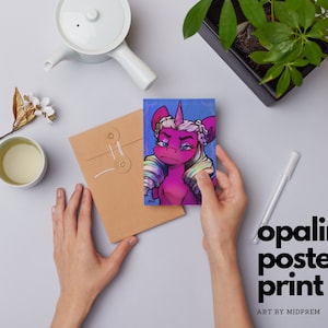Könnte beinhalten: Ein Poster-Druck mit einem magenta Einhorn mit strengem Blick, floralem Kranz und Regenbogenhaar. Das Kunstwerk vor blauem Hintergrund trägt den Text "opaline poster print" und "ART BY MIDPREM".