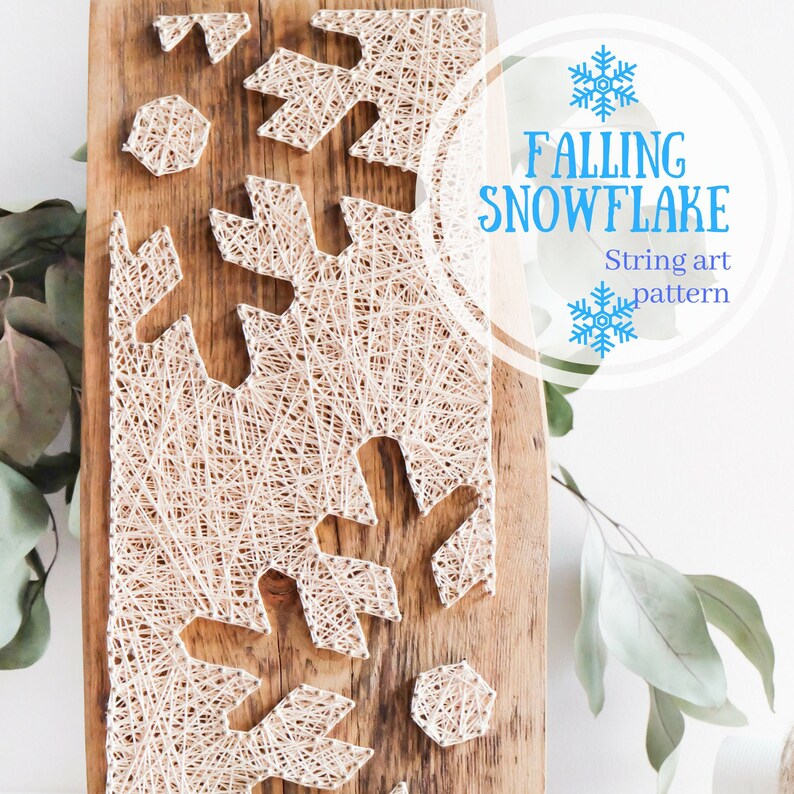 May include: A string art pattern of a snowflake falling on a wooden background. The pattern is made with white string and nails. The text "Falling Snowflake" and "String art pattern" is written in blue text on a white circle.