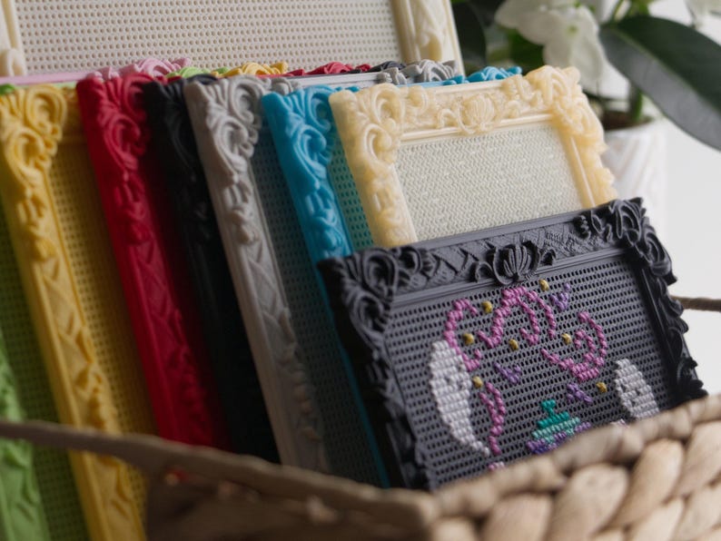 May include: A collection of rectangular pegboard frames in various colors including yellow, red, black, gray, blue, and cream. The frames feature ornate, molded edges and are arranged in a row. One black frame displays a colorful beaded design.