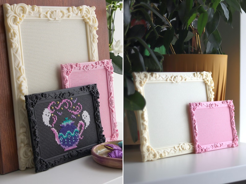 May include: A collection of rectangular frames with ornate, raised scrollwork borders in cream, pink, and black. The frames feature a grid-like interior surface. One black frame contains a cross-stitch design of a purple teapot with two white ghosts.
