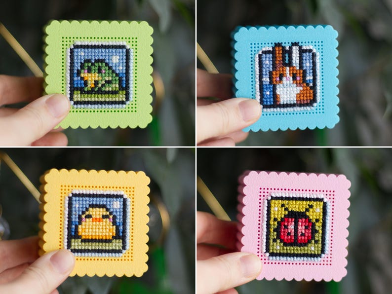 Four finished 3D printed cross stitch keepsake boxes held in hand — frog, rabbit, duck and ladybug designs stitched on perforated lids in green, blue, yellow and pink PLA