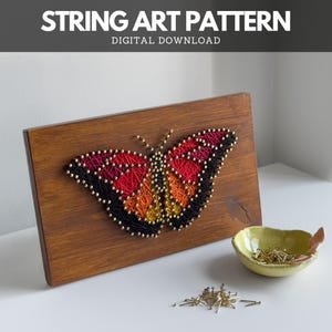 DIY butterfly string art finished using printable pattern – thread art sign on wooden board with brass nails and bowl on white desk