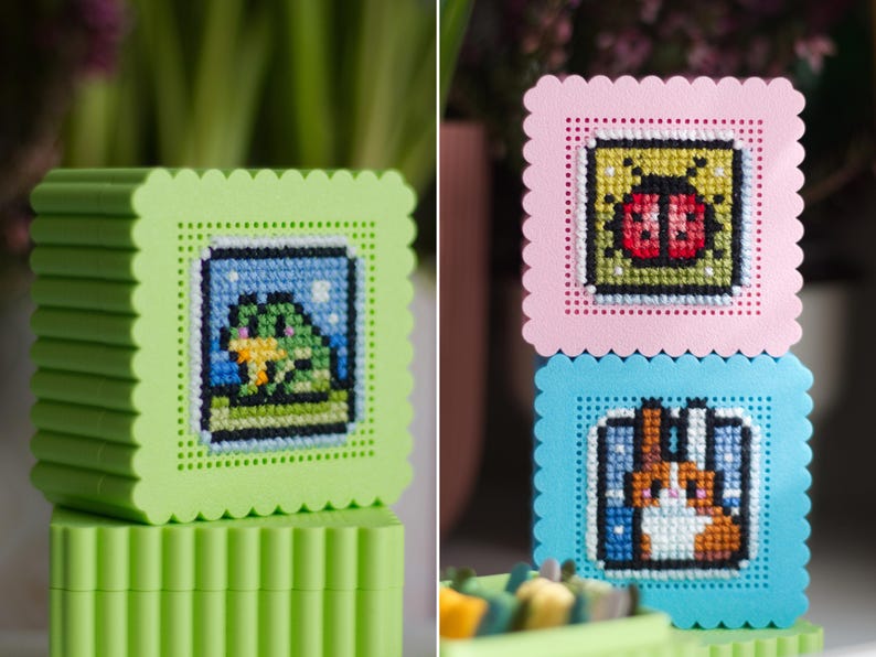 Stacked 3D printed cross stitch boxes — frog design on green box, ladybug and rabbit designs on stacked pink and blue boxes