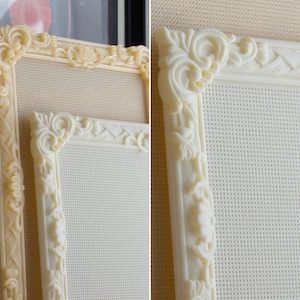 May include: Two rectangular frames featuring intricate, raised scrollwork and floral relief patterns along the borders. The frames are off-white in color and contain a fine, grid-like mesh material within the center, providing a textured surface.