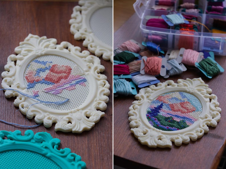 Cream baroque oval cross stitch frame with a floral design being stitched directly into the frame, shown with embroidery floss and a teal frame nearby. Stitchable frame printed from the STL file.