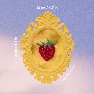 Yellow baroque oval cross stitch frame with a stitched strawberry design, labelled with dimensions 16 × 12 cm and 7 mm thick. Stitchable frame printed from the STL file.