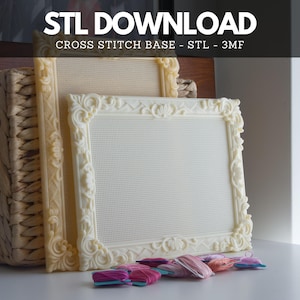 May include: Two off-white rectangular cross stitch bases with ornate, decorative frames and a grid-patterned center. The text STL DOWNLOAD CROSS STITCH BASE - STL - 3MF is visible at the top. Several small spools of colorful embroidery thread lie below.