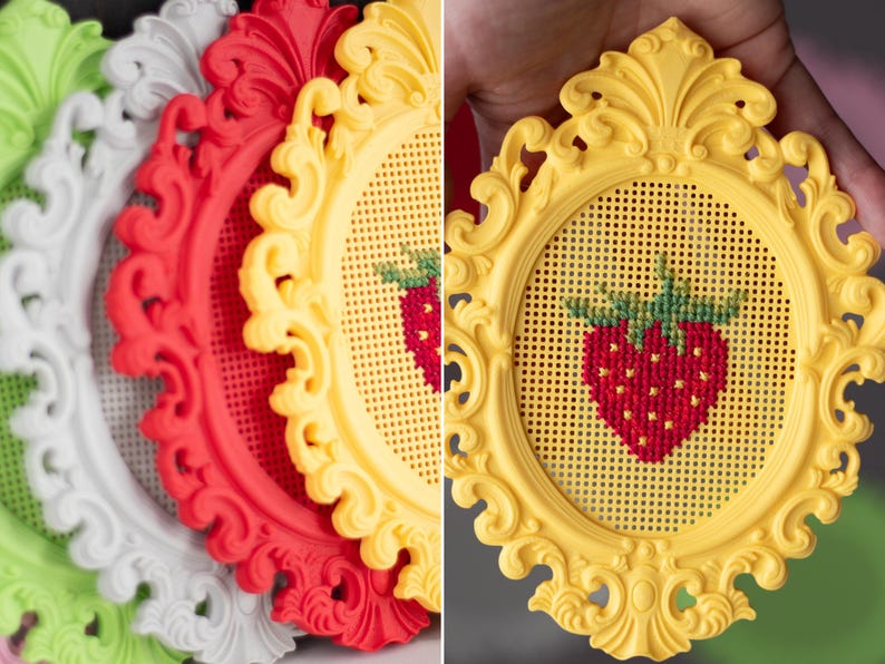 Baroque oval cross stitch frames in white, red, yellow and green, with a close-up of a yellow frame held in hand showing a finished strawberry design. Stitchable frames printed from the STL file.