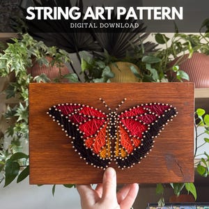 DIY butterfly string art finished using printable pattern – thread art sign on wooden board with brass nails and bowl on white desk