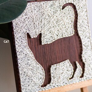 Stress relief craft kit for adults with cat silhouette string art on stained wood base, relaxing beginner DIY hobby project.