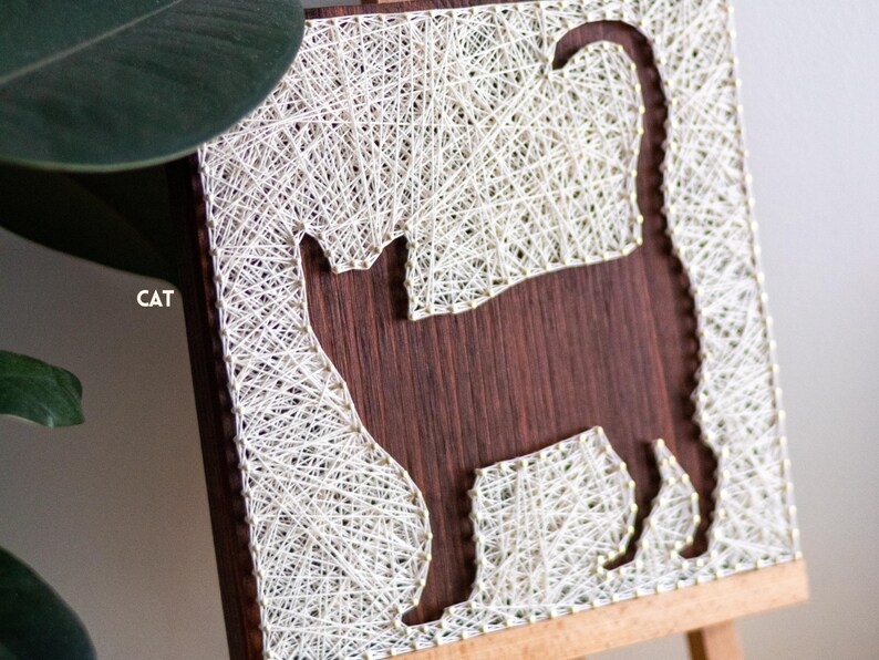 Stress relief craft kit for adults with cat silhouette string art on stained wood base, relaxing beginner DIY hobby project.