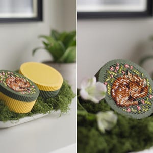 Round cross stitch box STL file — 3D printed yellow and green keepsake box with sleeping fawn embroidery on the lid, shown open and in close-up detail