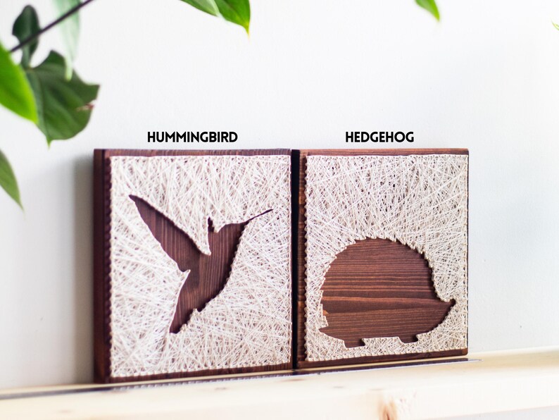 Stress relief craft kit for adults with hummingbird and hedgehog string art designs on stained wood base, relaxing DIY hobby project.