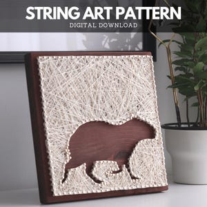 Könnte beinhalten: Ein String-Art-Stück auf Holz mit einer Capybara-Silhouette. Das Kunstwerk besteht aus weißem Faden auf einem dunkelbraunen Holzbrett. Der Text "STRING ART PATTERN DIGITAL DOWNLOAD" ist oben zu sehen.