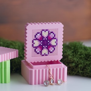 Open 3D printed pink cross stitch keepsake trinket box with purple flower embroidery on perforated lid, used as a jewellery boxOpen 3D printed pink cross stitch keepsake trinket box with purple flower embroidery on perforated lid, used as a jewellery box