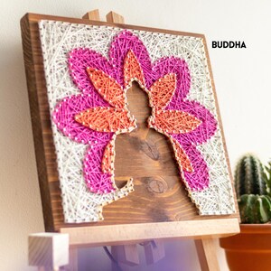 Stress relief craft kit for adults featuring Buddha silhouette with colorful string art flower design on stained wood base.