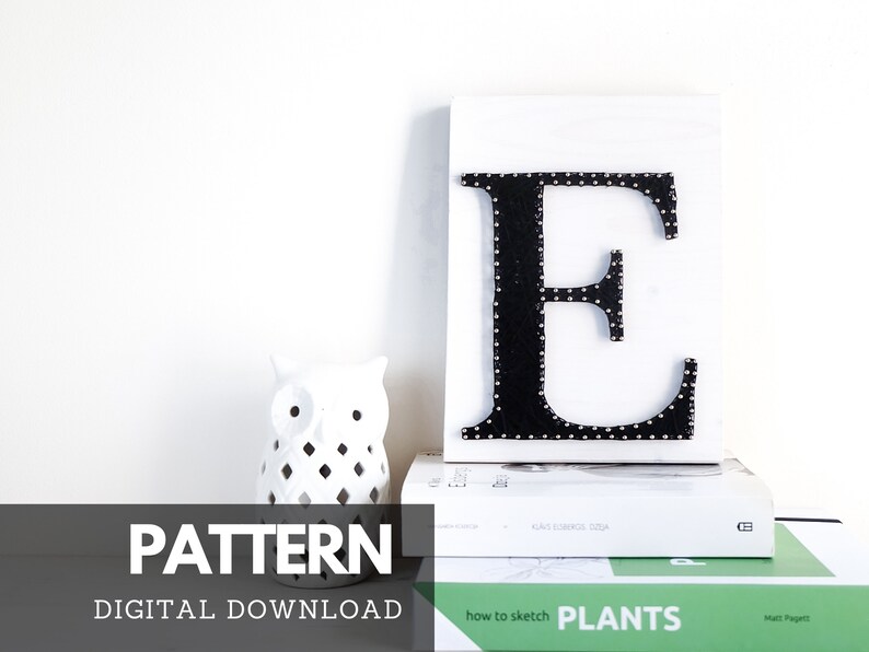 May include: A digital download pattern for a nail hammered letter E. The letter is black and the nails are silver. The letter is on a white background. The pattern is for a DIY project.