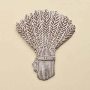 May include: A decorative wall hanging in the shape of a wheat sheaf. The piece is made of a light grey material with detailed textures, including individual wheat stalks and a tied bundle. The background is a solid, light beige colour.