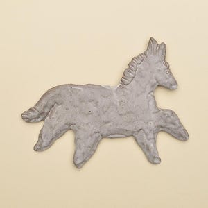 Op de afbeelding: Een grijze, handgemaakte paardenfiguur met een textuuroppervlak. Het paard wordt afgebeeld in een rennende pose, met uitgestrekte benen. De figuur staat tegen een lichtbeige achtergrond.
