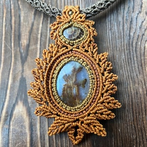 May include: A brown and gold macrame necklace with a large oval agate pendant and a smaller round ammonite pendant.