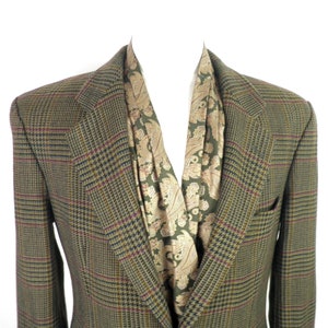 Puede incluir: Una chaqueta de traje de cuadros marrones, verdes y rojos con una bufanda de estampado paisley.