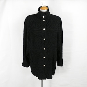 Pode incluir: Uma camisa preta de botões com um padrão texturizado. A camisa tem uma gola alta e mangas compridas.