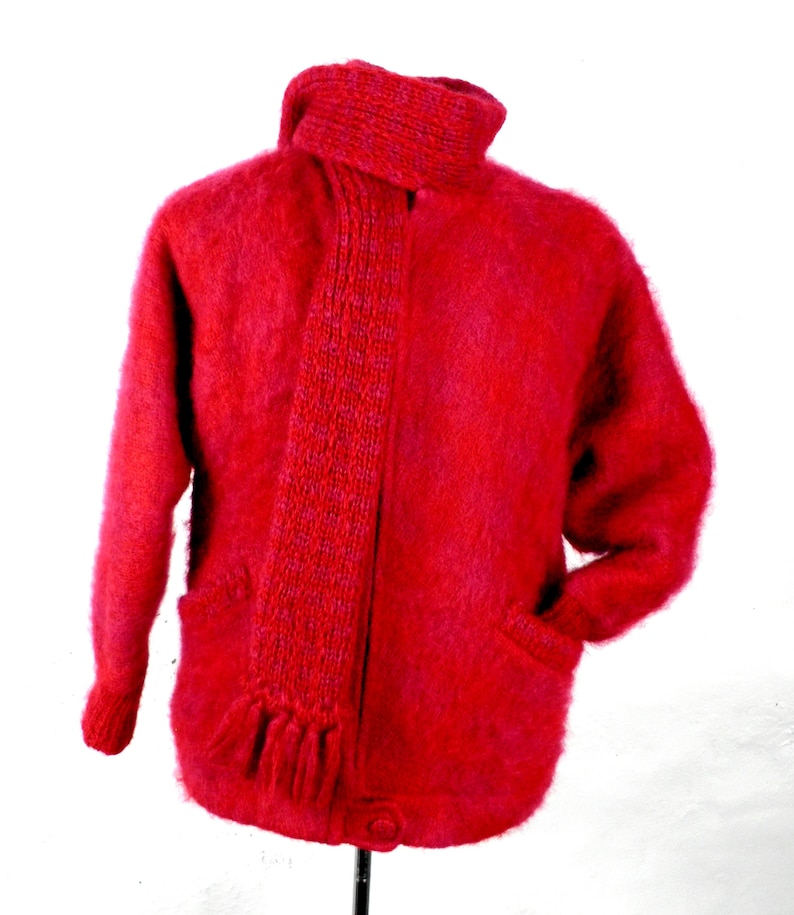 May include: A red fuzzy cardigan with a matching red and purple scarf. The cardigan has two pockets and a button closure.