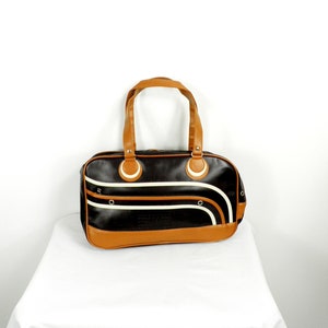 May include: A brown and black leather satchel bag with white stripes and a top handle.