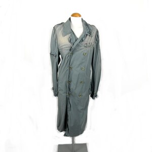 May include: A long, gray, double-breasted coat with a large collar and a distressed look. The coat has a zipper closure and multiple buttons.