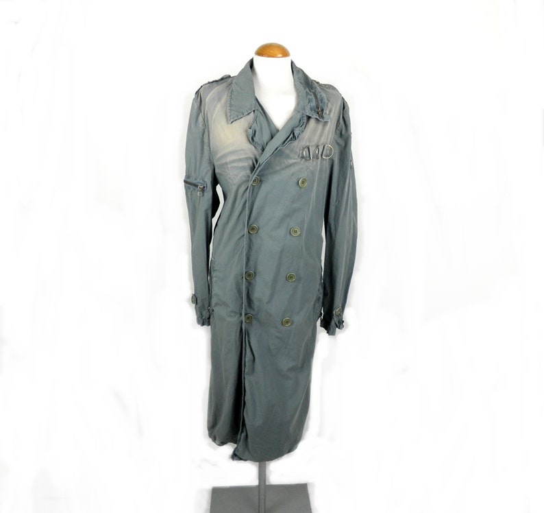 May include: A long, gray, double-breasted coat with a large collar and a distressed look. The coat has a zipper closure and multiple buttons.