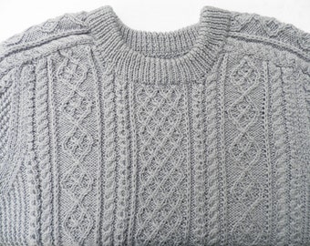 May include: A gray knitted sweater with a cable knit pattern.