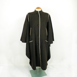 May include: A brown wool cape with a high collar and a cream trim. The cape has a long, flowing silhouette and is fastened with buttons down the front.