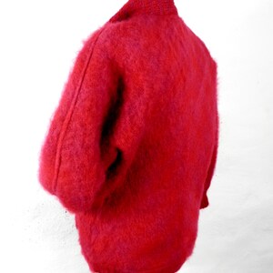 May include: A fuzzy red cardigan sweater with a high collar.