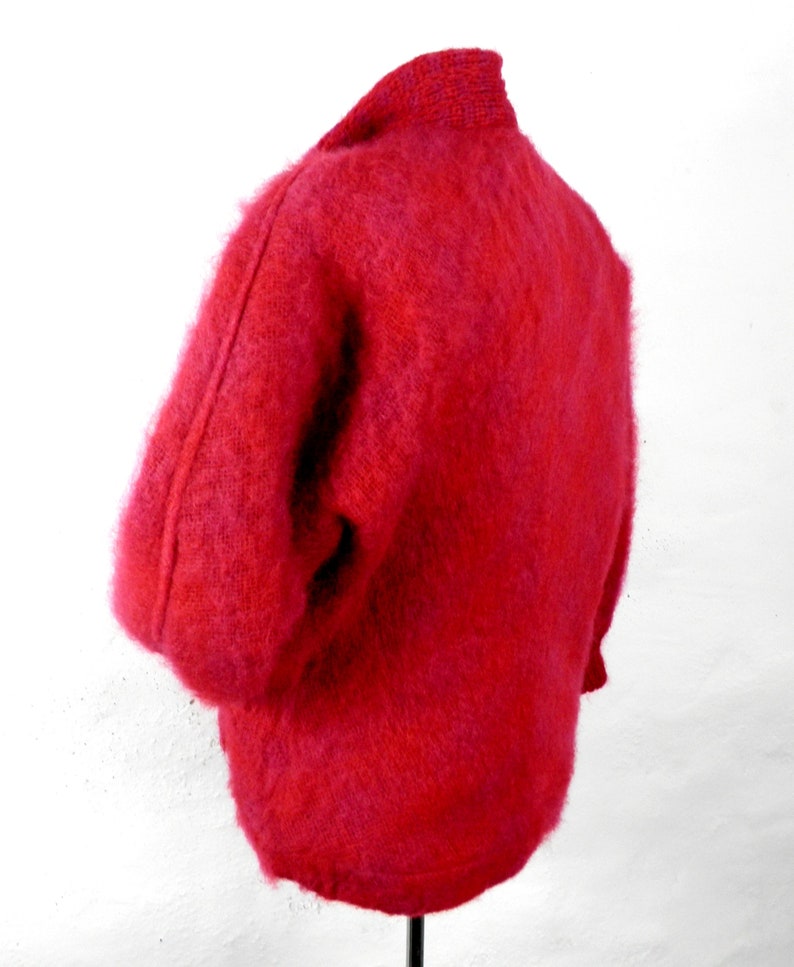May include: A fuzzy red cardigan sweater with a high collar.